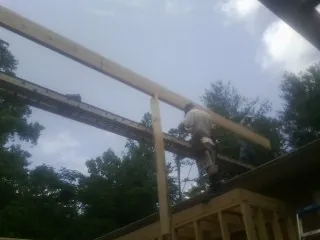 Carpenter setting a ridge beam over a new addition frame — Ice Dam Removal by Roofing Brothers in Boykins