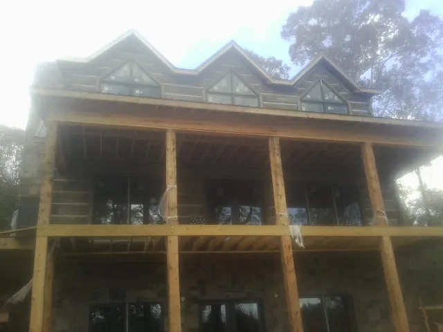 Dormers and porch framing on a large log home under construction — Roof Coating work by our crew in Boykins