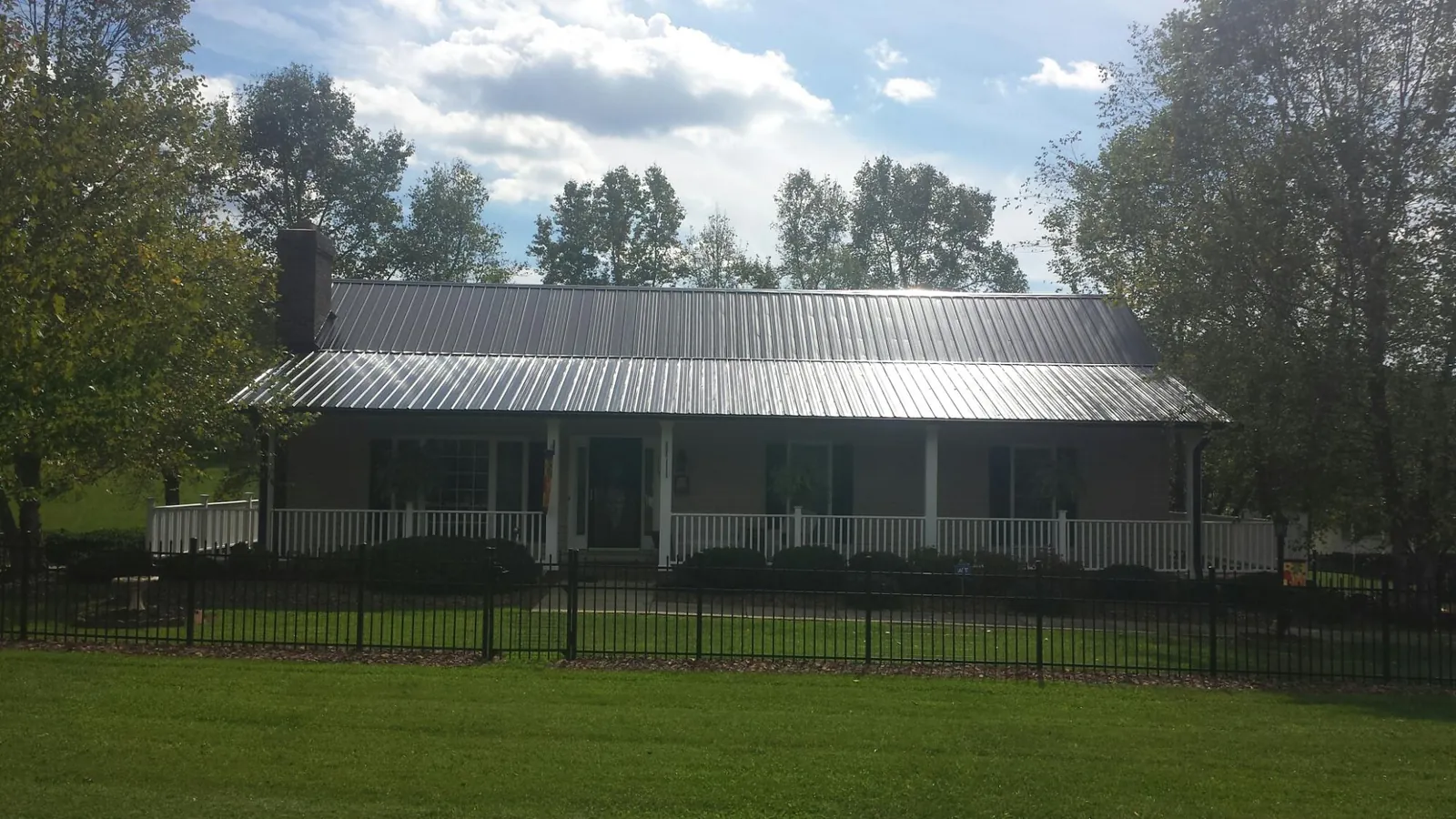Gray metal roof on a brick ranch with a full width front porch — Gutter Guard Installation work by our crew in Boykins