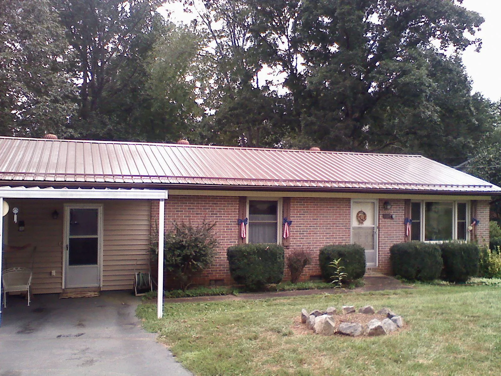 Bronze metal roof and carport on a brick ranch home — Roof Repair work by our crew in Boykins