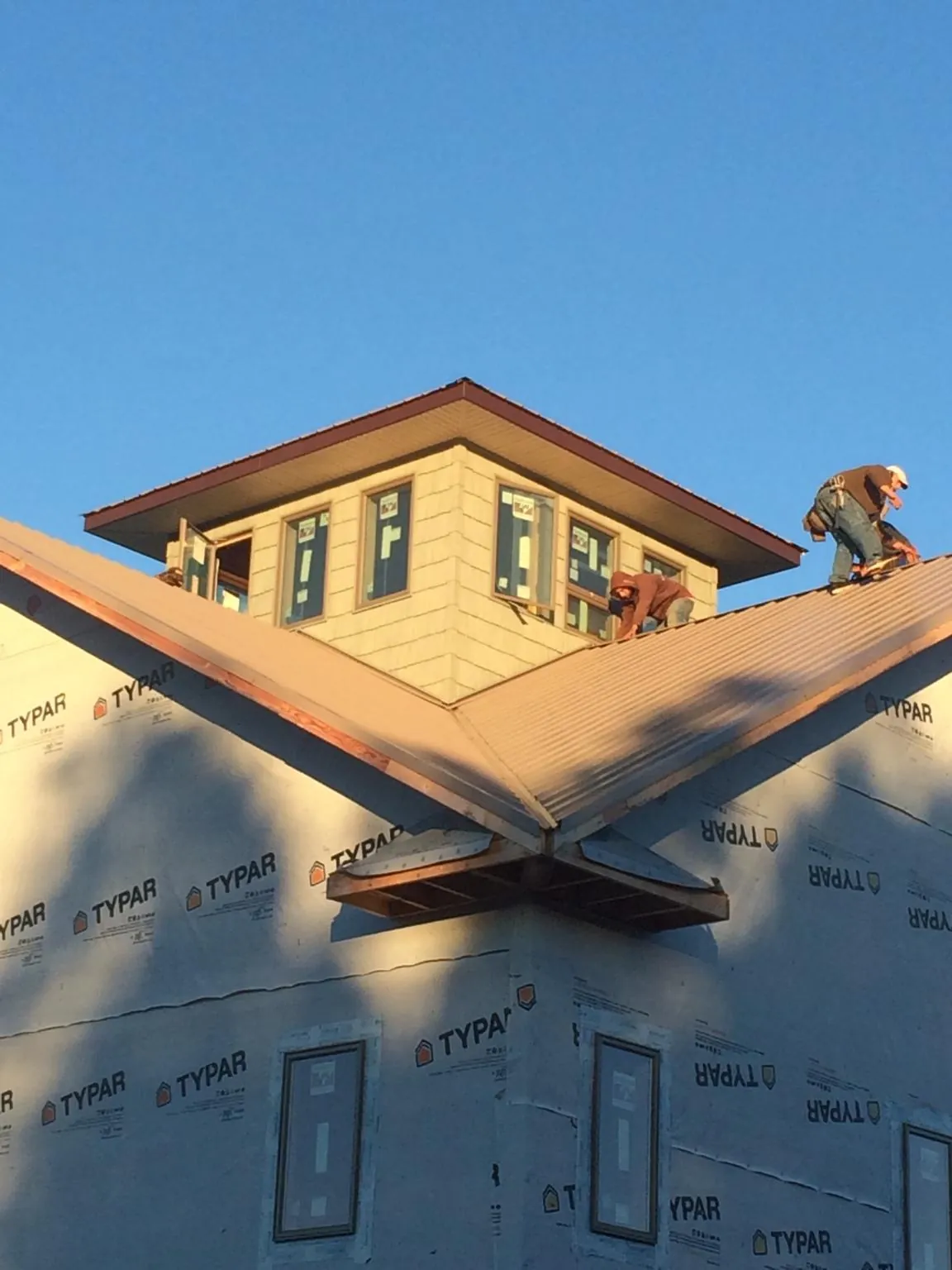 Roofers working around a rooftop cupola on a new metal roof at sunset — Roof Waterproofing in Boykins by Roofing Brothers
